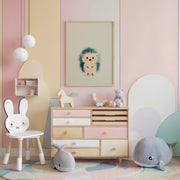Cozy children's room featuring pastel-colored furniture, a framed print of a cute tiny hedgehog, soft plush toys shaped like sea animals, and a bunny-themed chair.