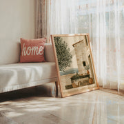 Olive Terrace Tuscany print, stone house and terrace by an olive tree, shown in a room