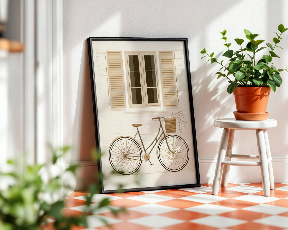 A framed art print leaning against a wall on a checkered terracotta and white floor, featuring a vintage bicycle and shuttered window. A small white stool with a potted green plant sits to the right.