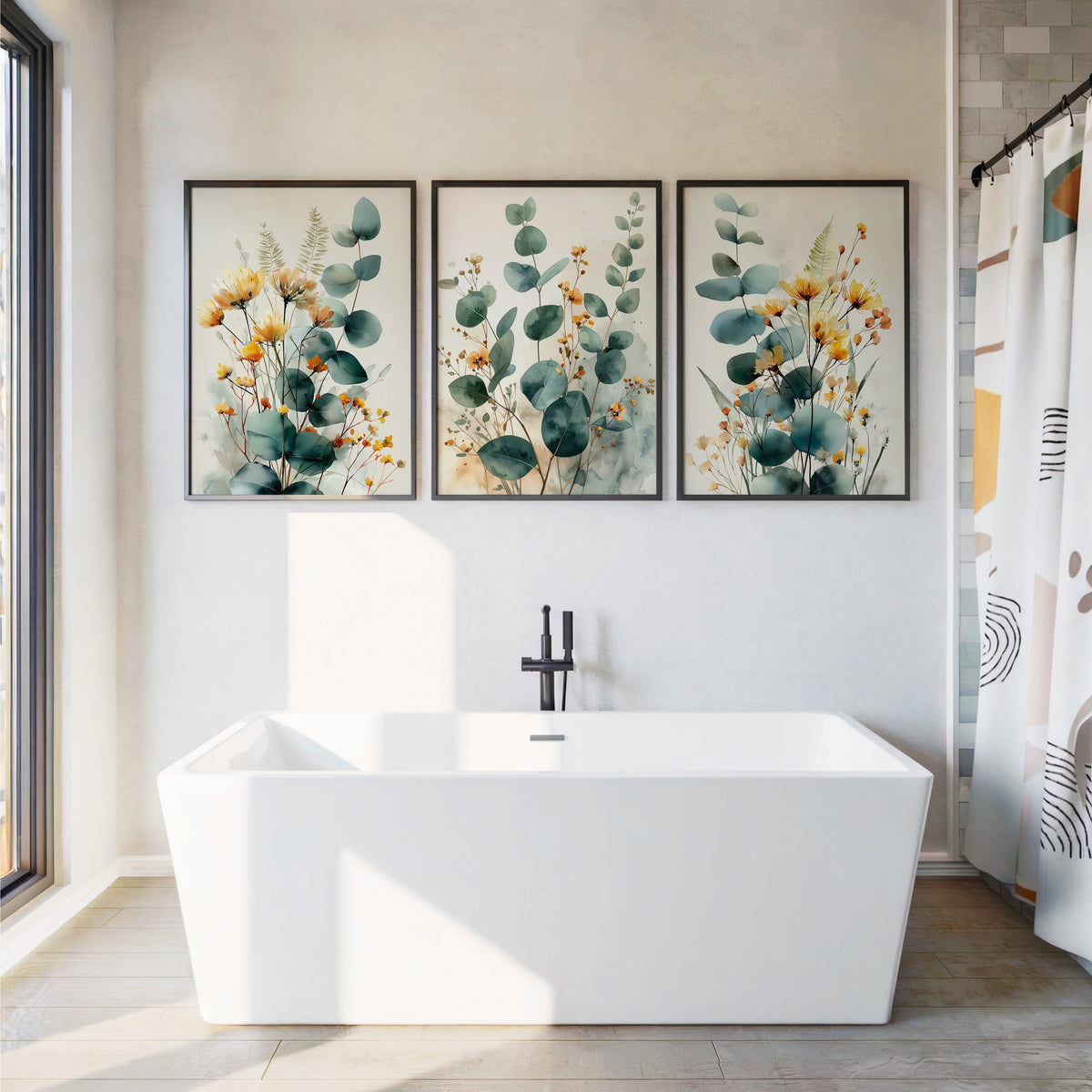 Three framed botanical wall art prints with green eucalyptus leaves and yellow flowers hang above a white freestanding bathtub in a bright bathroom.